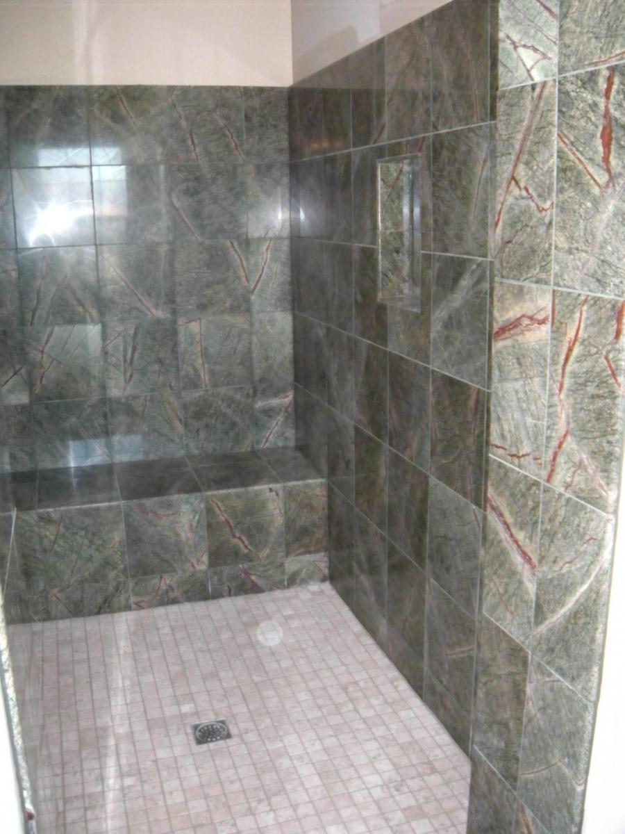 Picture of This master shower features 12x12 green forest marble tile a closed face shower bench and 2x2 floor tile. - DC Tile and Stone