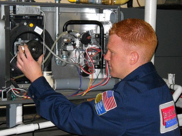 Picture of A Service Champions technician works on a customer's HVAC system. - Service Champions