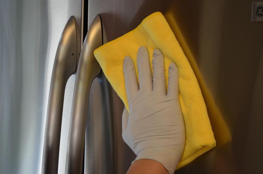 Picture of An Elite Pro Home Cleaning employee uses a microfiber cloth to clean a refrigerator. - Elite Pro Home Cleaning