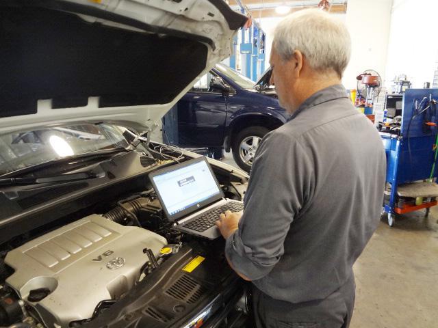 Picture of President Bill Faulconer performs a computer diagnostic test on a customer's vehicle. - Renson Automotive