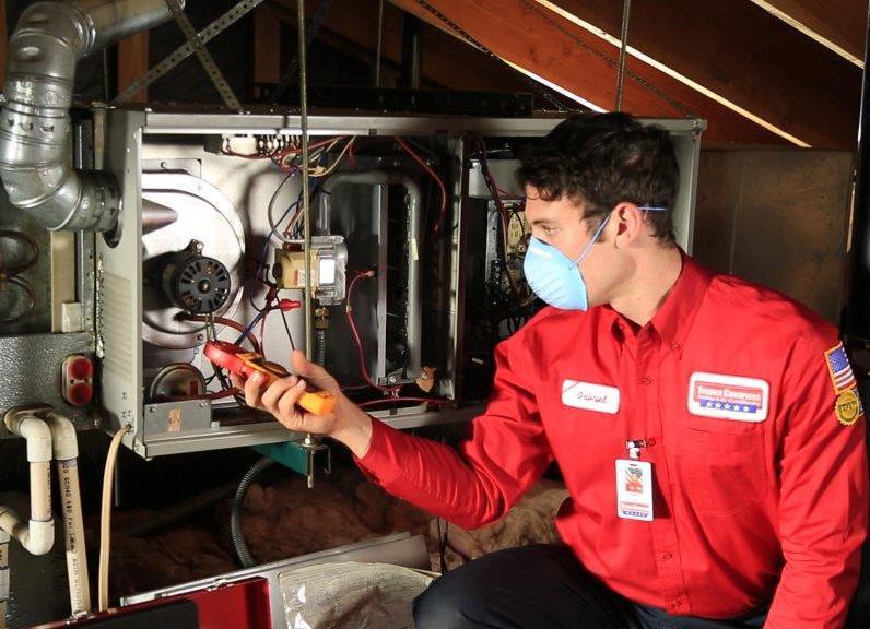 Picture of A Service Champions technician works on a customer's HVAC system. - Service Champions