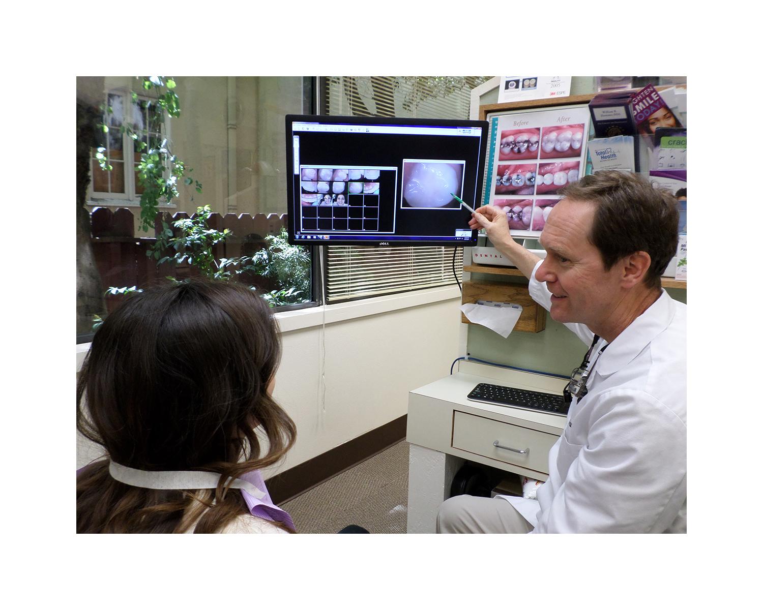 Picture of Dr. Hummer goes over a set of dental photos with a patient. - William R. Hummer, DDS