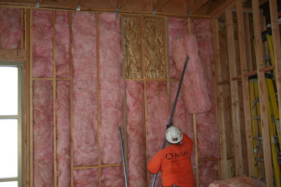 Picture of An Alcal Specialty Contracting employee works on an unfaced batt insulation project. - Alcal Specialty Contracting, Inc.