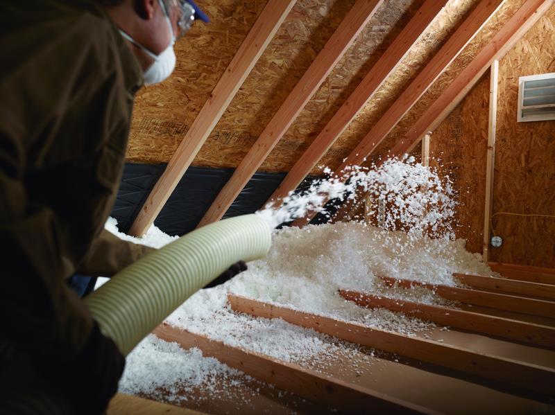 Picture of An Alcal Specialty Contracting employee installs Johns Manville Climate Pro® loose-fill insulation in an attic. - Alcal Specialty Contracting, Inc.