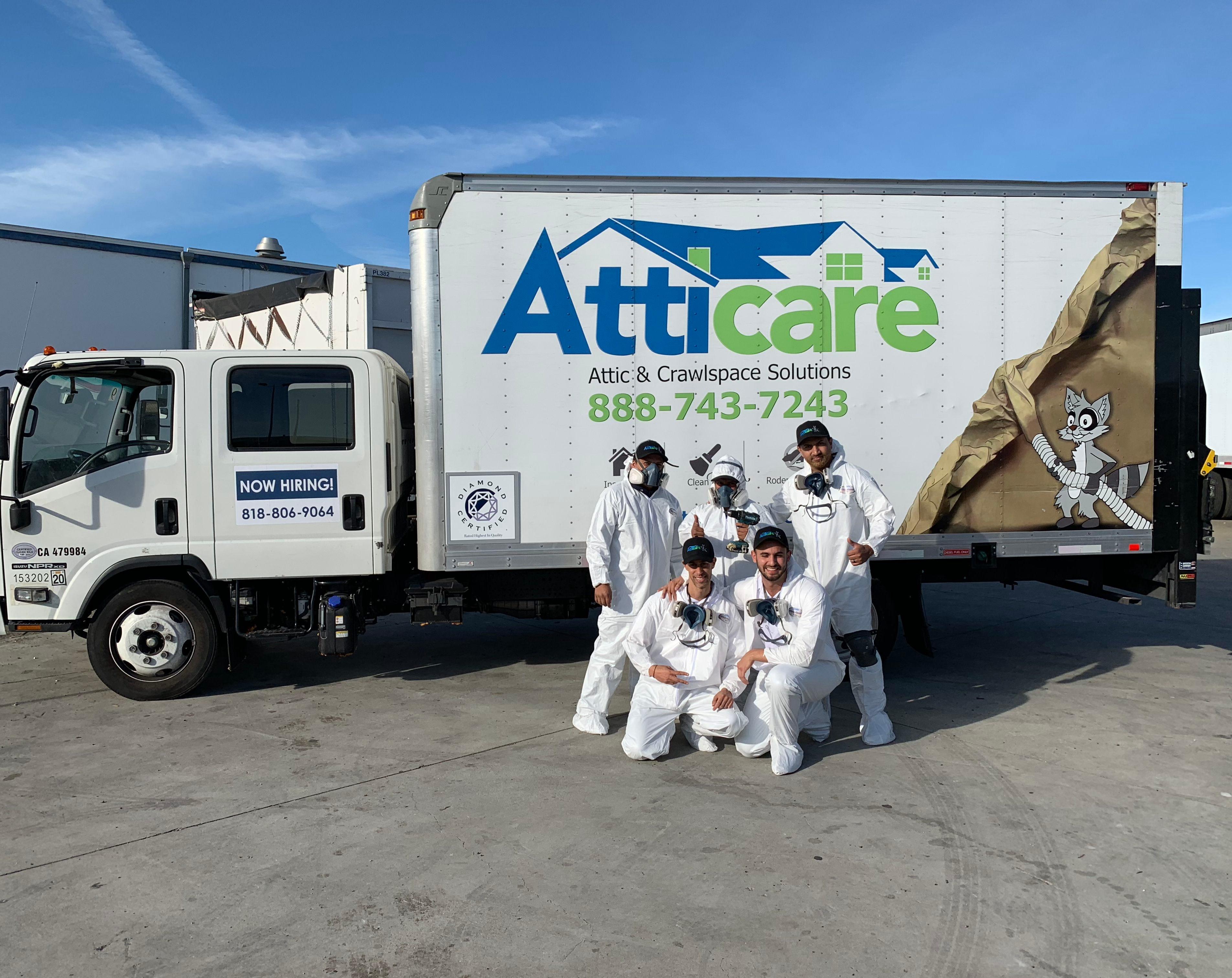 Picture of Atticare team members pose in front of one of the company's service trucks. - Atticare Construction
