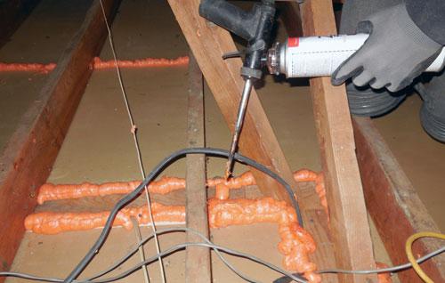 Picture of An Atticare technician air-seals a client's attic. - Atticare Construction