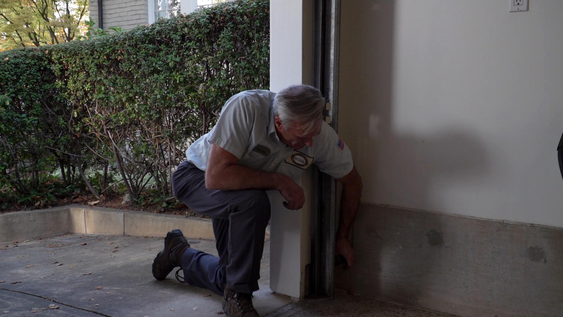 Picture of A Precision Door Services of the Bay Area technician checks a garage door's sensors. - Precision Door Services of the Bay Area