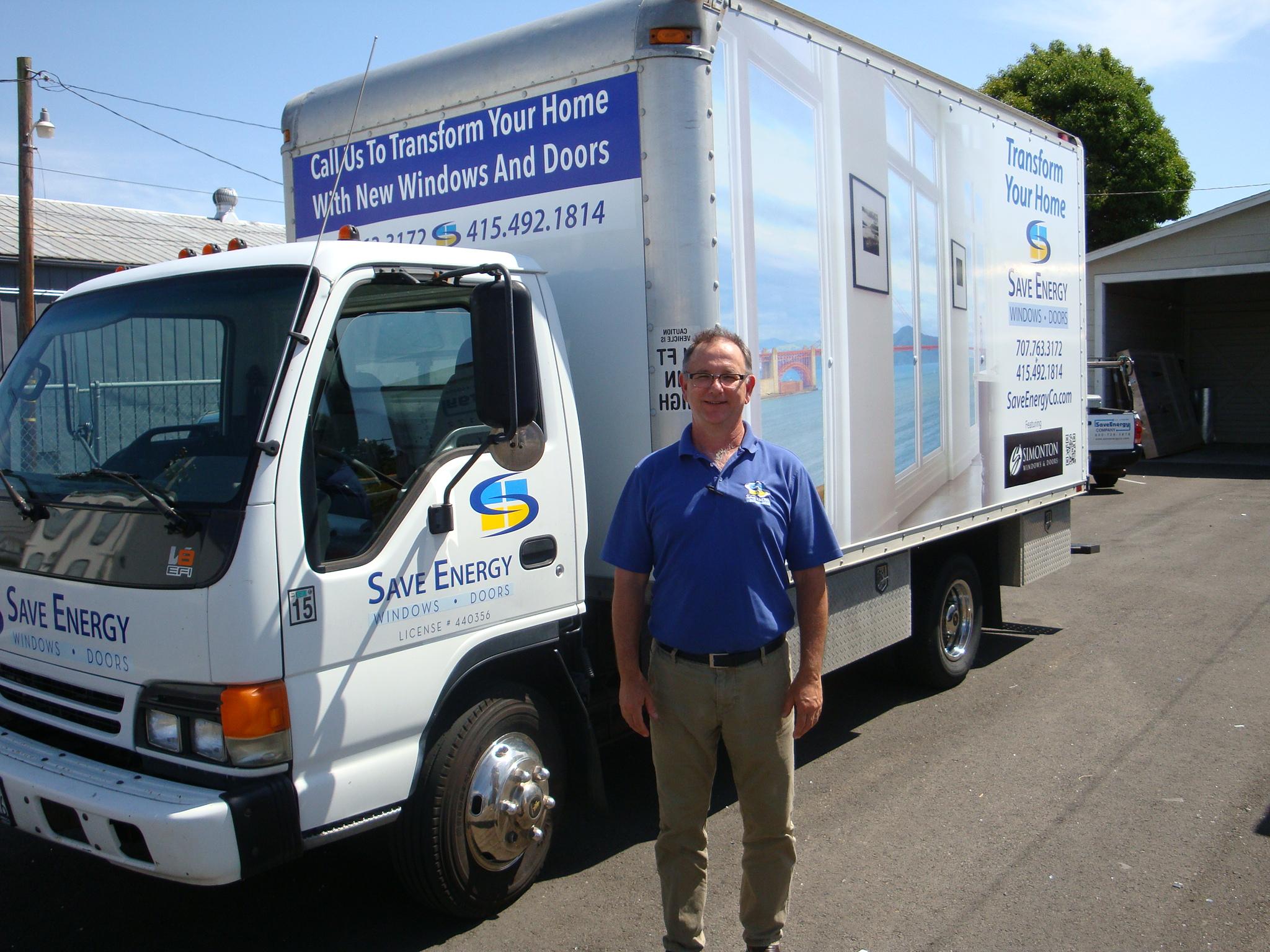 Picture of John Gorman owner and president of Save Energy Company proudly stands next to a newly wrapped production truck. It serves as a mobile billboard for the company as well as an onsite workshop for the installation crews. - Save Energy Company