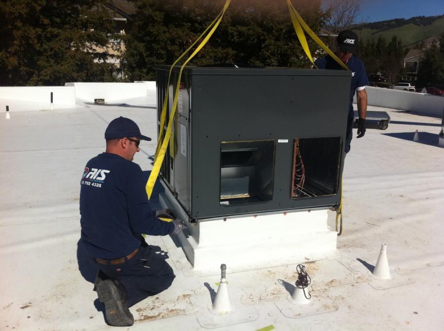 Picture of An AIS Heating & Air Conditioning technician installs a new commercial unit on a roof. - AIS Heating & Air Conditioning