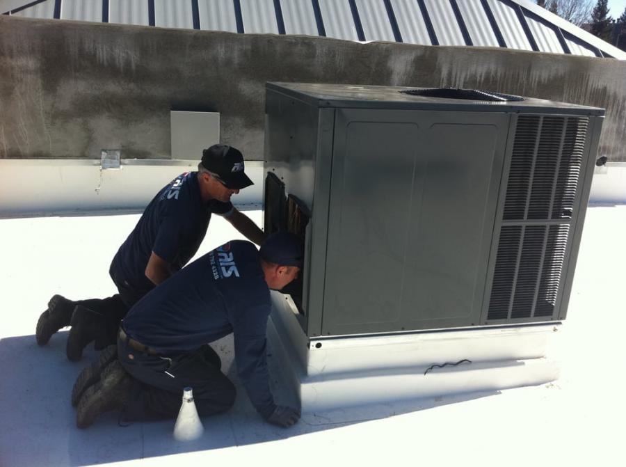 Picture of Owner Daniel Sojkic (L) and his son work on an HVAC unit. - AIS Heating & Air Conditioning