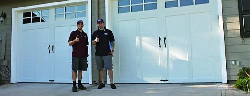 Picture of Two Door Pros technicians stand in front of a recently finished garage door installation. - Door Pros, Inc.