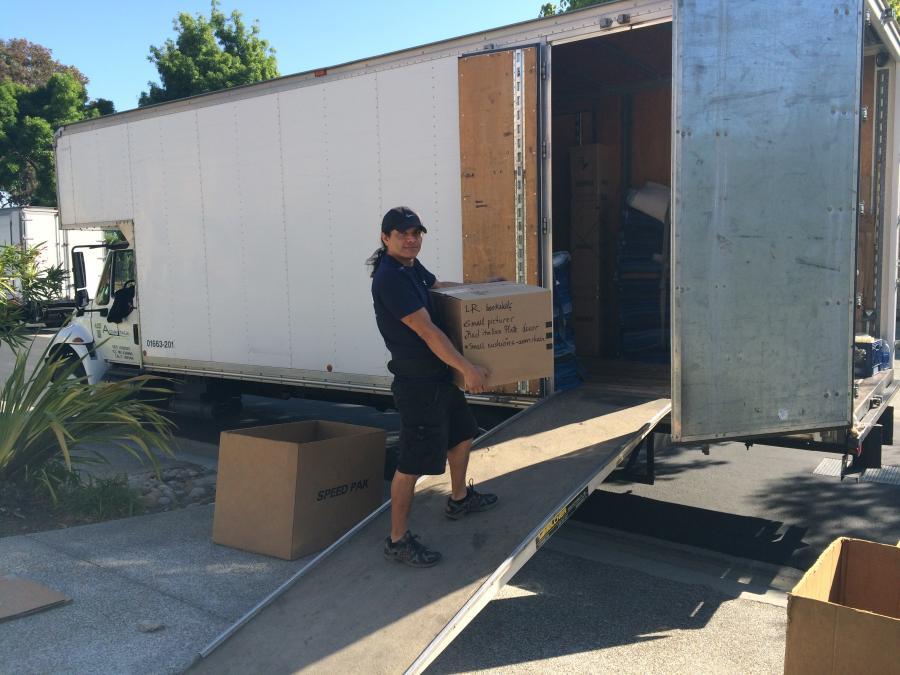 Picture of An Advantage Moving & Storage employee loads a box into one of the company's moving trucks. - Advantage Moving & Storage