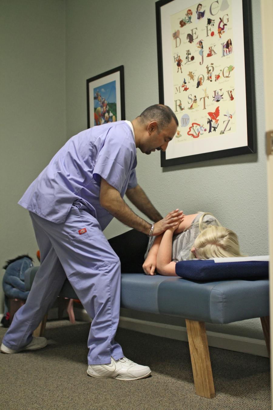Picture of Dr. Dhesi prepares to perform a lower back maneuver. - Springtown Wellness Center - Jag Dhesi, D.C.