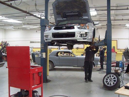 Picture of One of B2 Perfection Auto Body's technicians uses a lift to work on a customer's car. - B2 Perfection Auto Body