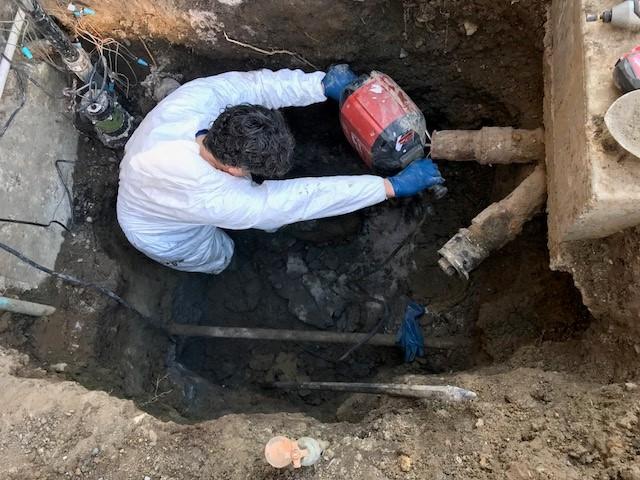 Picture of An Absolute Plumbing and Drain technician excavates and jackhammers an existing concrete slab to make room for a sewer injector system. - Absolute Plumbing and Drain