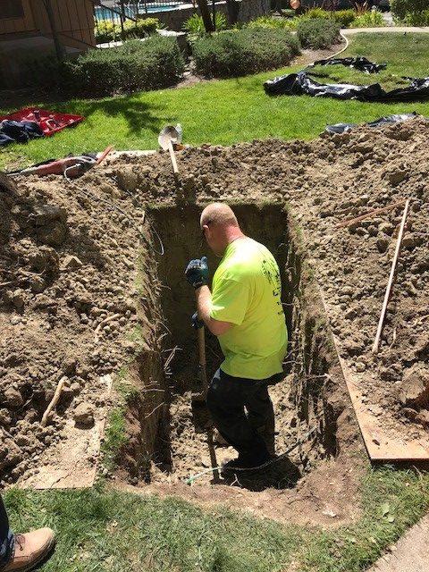Picture of An Absolute Plumbing and Drain technician hand-excavates a client's yard for a sewer repair. - Absolute Plumbing and Drain