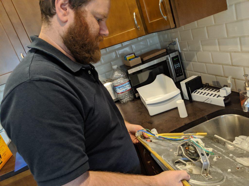 Picture of Co-owner Natan Framowitz checks a broken refrigerator fan system. - FixEm Appliance Repair