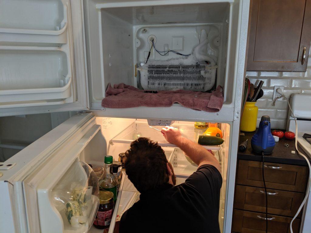 Picture of Co-owner Natan Framowitz repairs a customer's refrigerator. - FixEm Appliance Repair