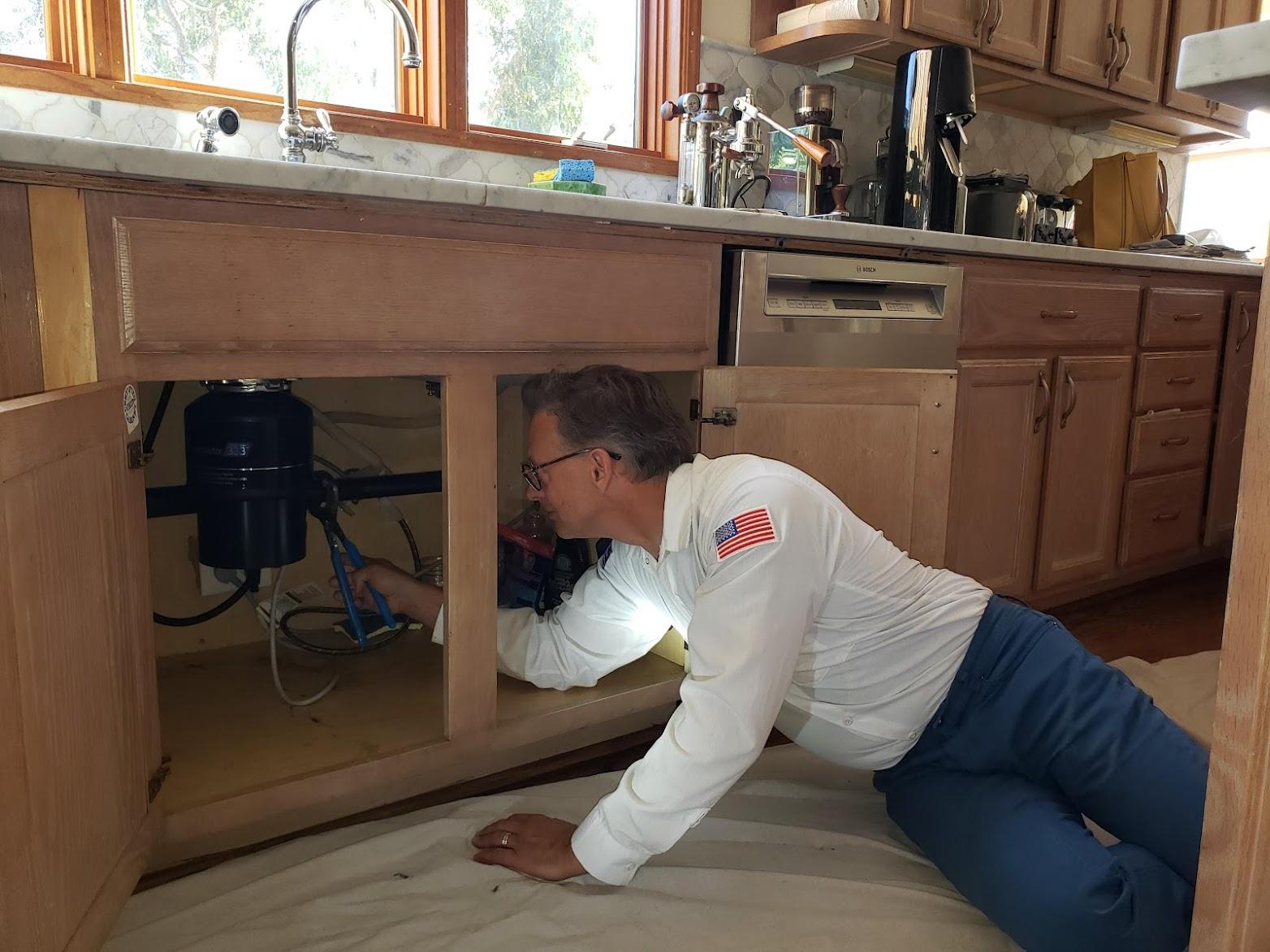 Picture of A Big Blue Plumbing technician installs a garbage disposal. - Big Blue Plumbing