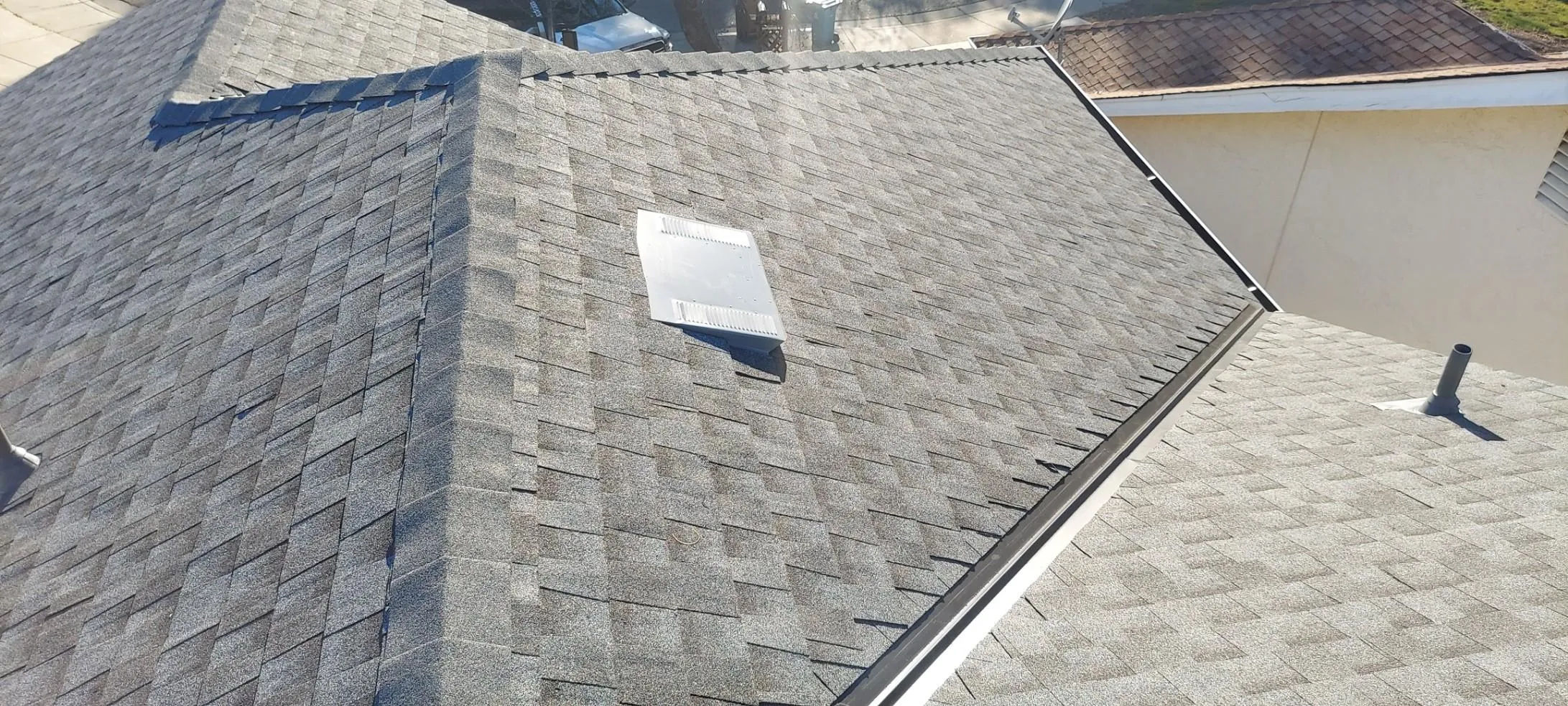 A newly installed shingle roof with a vent, featuring clean lines and precise craftsmanship. A newly installed shingle roof with a vent, featuring clean lines and precise craftsmanship.