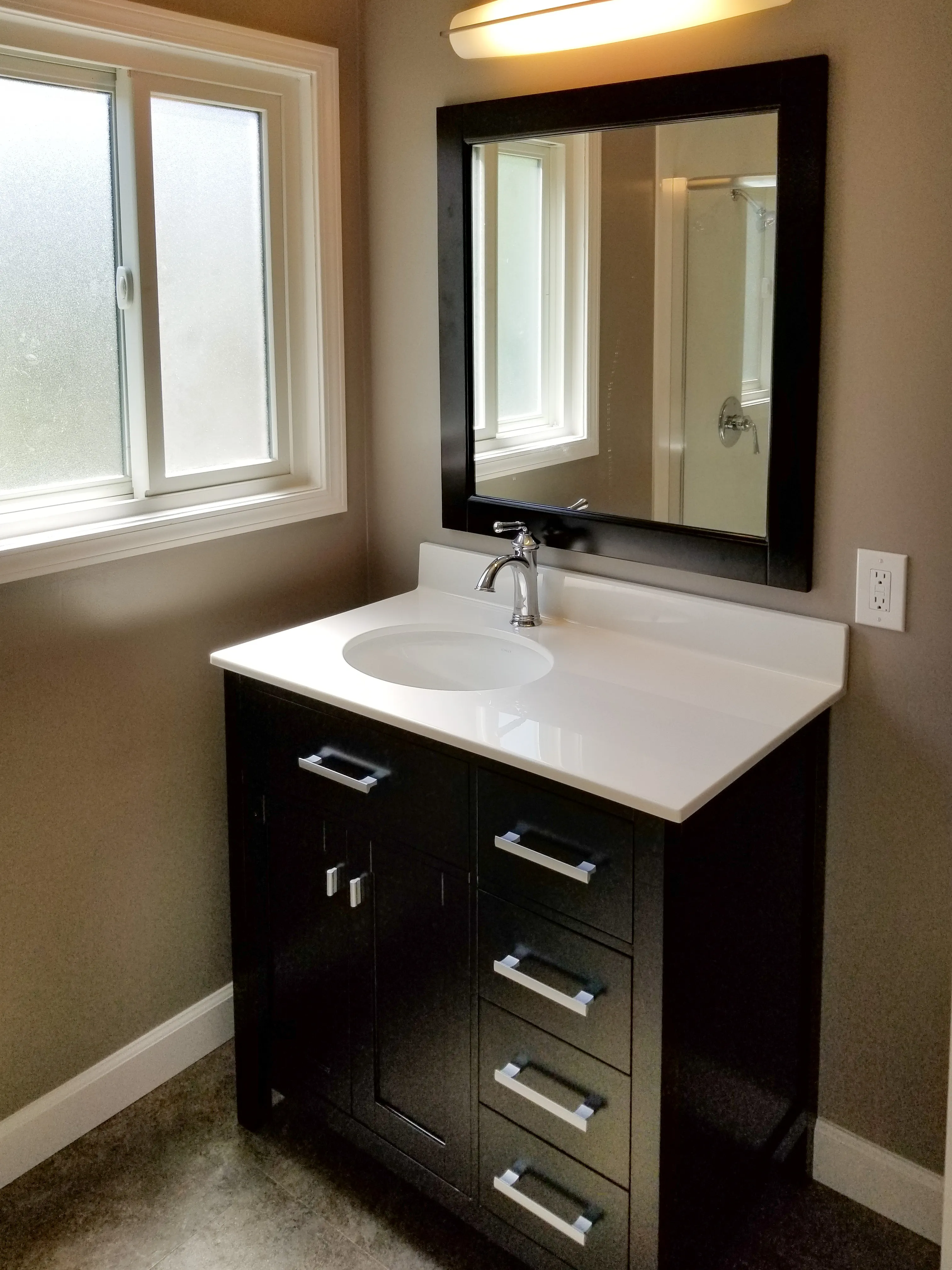 Picture of In a serene bathroom setting, a sleek black vanity with a polished white countertop is complemented by modern fixtures and a large mirror. Dahme Construction showcases their commitment to quality outcomes, enhancing spaces with understated elegance. Copyright ©2025 Diamond Certified Resource - Dahme Construction