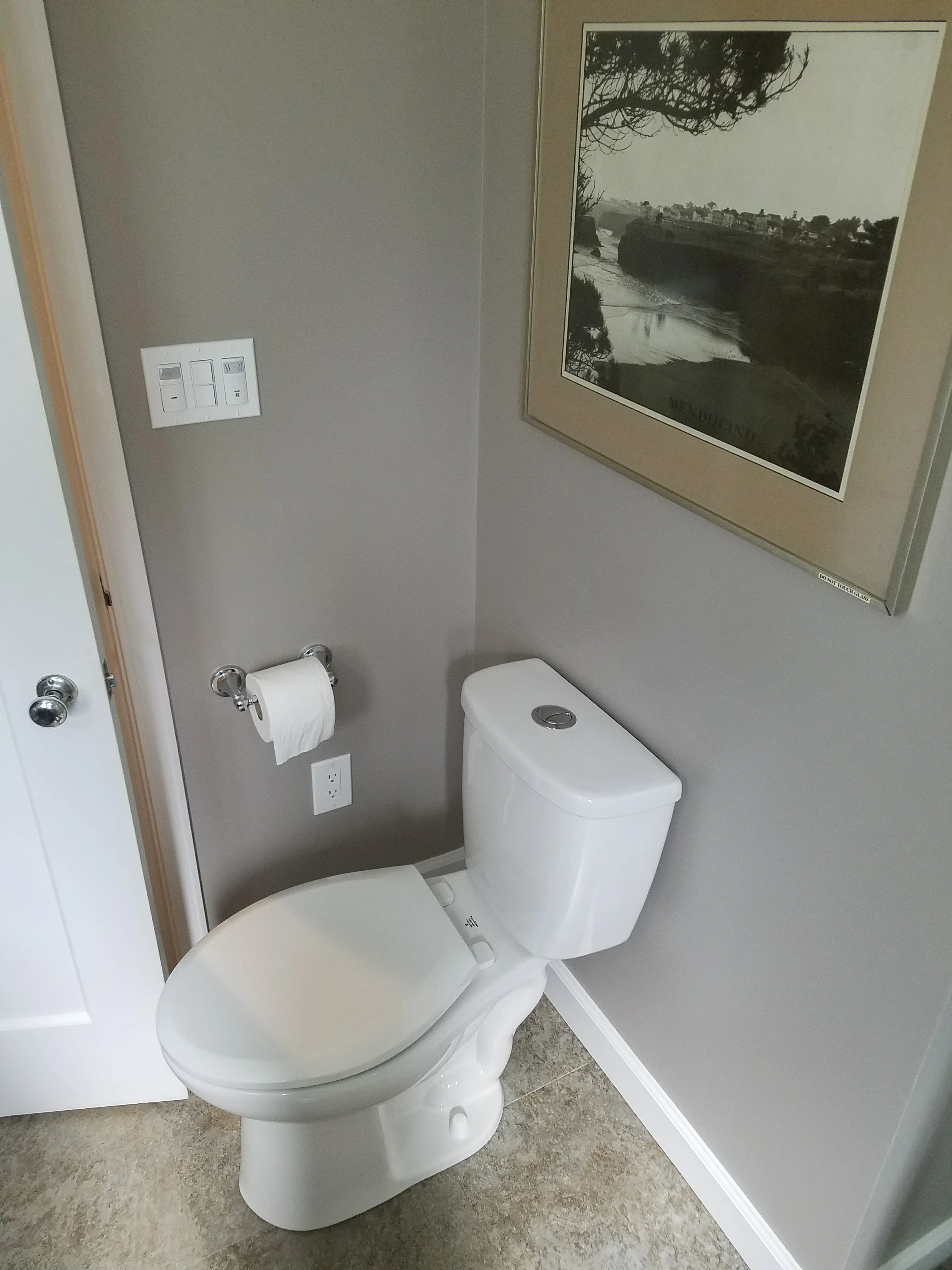 Picture of In a serene bathroom corner, a sleek toilet beside a neatly arranged toilet paper holder exemplifies Dahme Construction's focus on quality outcomes. The subtle interplay of modern fixtures and a tranquil wall print reflects the companyâ€™s commitment to excellence. Copyright ©2025 Diamond Certified Resource - Dahme Construction