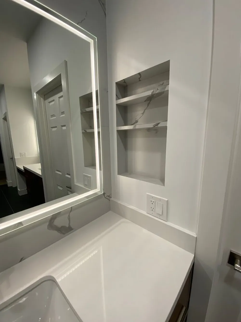 Picture of A sleek, modern bathroom vanity with clean lines and built-in shelving showcases Design Miter Tile's commitment to quality outcomes. The illuminated mirror adds a touch of elegance to the design. Design Miter Tile is recognized for expertise and quality in every project. Copyright ©2025 Diamond Certified Resource

 - Design Miter Tile