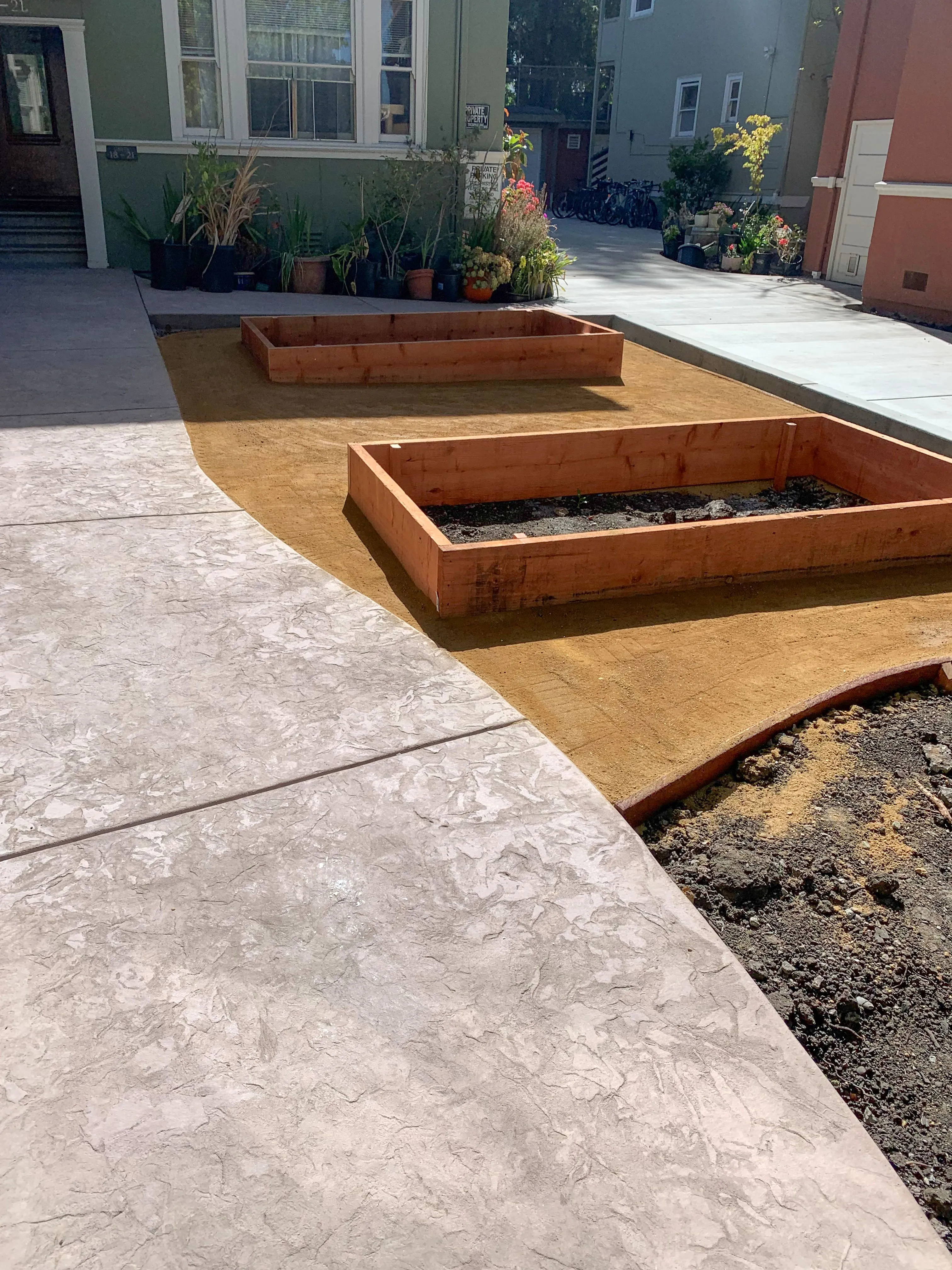 Picture of Raised wooden garden beds sit ready for planting beside newly laid concrete paths, showcasing ARP Hardscape's commitment to quality outcomes. Copyright ©2025 Diamond Certified Resource - ARP Hardscape