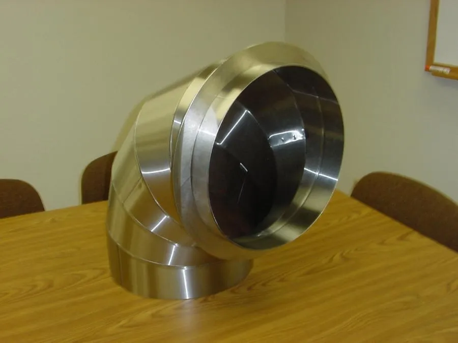 Picture of A sleek, polished metal duct elbow sits on a wooden table, showcasing Bell Products, Inc.'s commitment to quality outcomes. Their expertise in crafting precision HVAC components consistently earns them a Highest in Quality rating. Copyright ©2025 Diamond Certified Resource. - Bell Products, Inc.