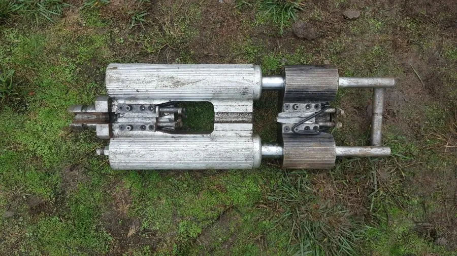  A metal pipe inspection tool rests on the ground covered in green moss and grass.