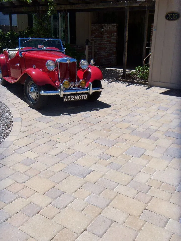 Picture of A classic red car gleams on a meticulously crafted driveway, showcasing The Legacy Paver Group's dedication to quality outcomes. The company's focus on excellence is evident in every detail. Copyright ©2025 Diamond Certified Resource - The Legacy Paver Group