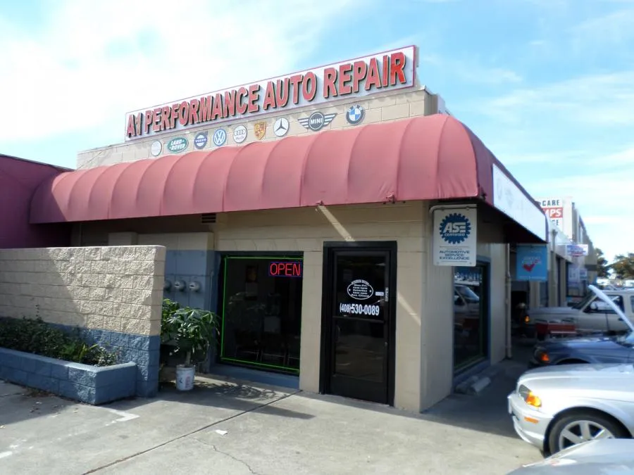  Auto repair shop with red awning, "A1 Performance Auto Repair" sign, and open sign on door. Adjacent cars are visible.