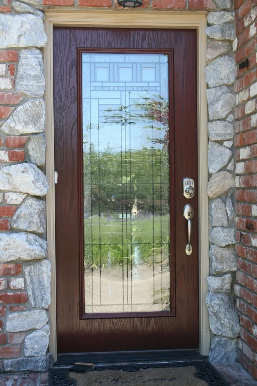 Picture of A beautifully crafted front door with a detailed glass panel reflects the serene surroundings. Quality First Home Improvement, Inc. ensures every installation, like this, achieves the highest standards of quality. Their dedication to quality outcomes is unmatched. Copyright ©2025 Diamond Certified Resource. - Quality First Home Improvement, Inc.