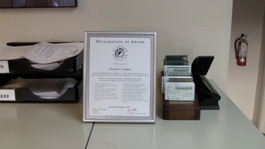 Picture of In the quiet corner of an office, Alexander Company's framed Diamond Certified award stands amidst business cards and documents, symbolizing their focus on quality outcomes. Copyright ©2025 Diamond Certified Resource

 - Alexander Company