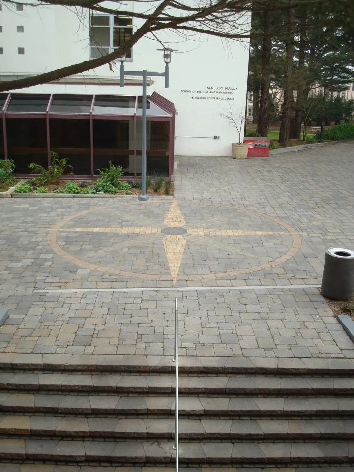 Picture of A beautifully crafted compass rose design adds a touch of elegance to the paved walkway outside Malloy Hall, showcasing The Legacy Paver Group's dedication to quality outcomes. Recognized for their expertise, they create spaces that blend function with artistry. Copyright ©2025 Diamond Certified Resource - The Legacy Paver Group