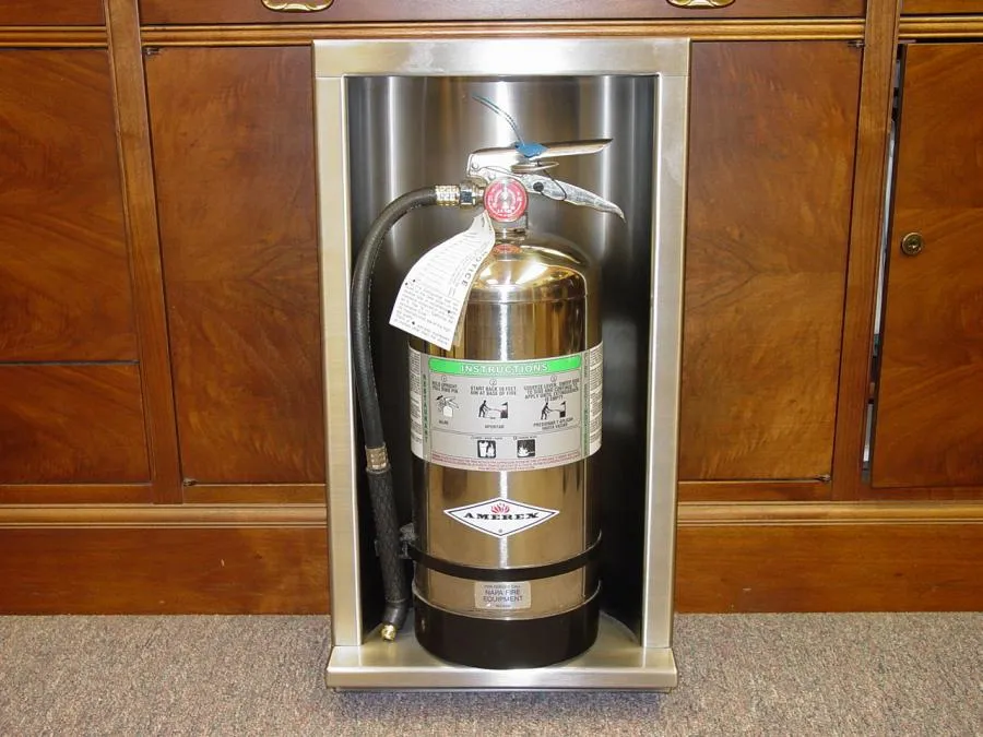 Picture of Nestled within a sleek metal recess, a fire extinguisher rests against a backdrop of polished wood cabinetry, exemplifying Bell Products, Inc.'s focus on quality outcomes. The company's commitment to safety and reliability is underscored by this meticulous installation. Copyright ©2025 Diamond Certified Resource. - Bell Products, Inc.