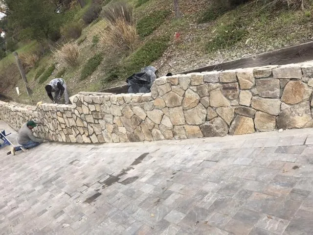 Picture of  Workers meticulously align stones on a retaining wall, reflecting Bay Area Drainage, Inc.'s commitment to quality outcomes. This attention to detail has earned them Diamond Certified recognition. Copyright ©2025 Diamond Certified Resource.

 - Bay Area Drainage, Inc.