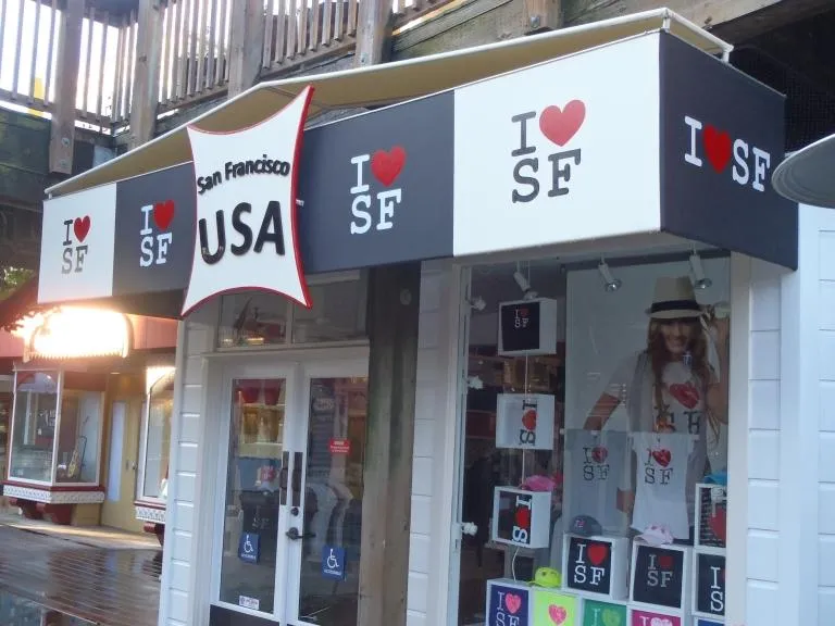  A storefront featuring "I ❤️ SF" signs and merchandise, with a display window showcasing T-shirts and accessories inside.