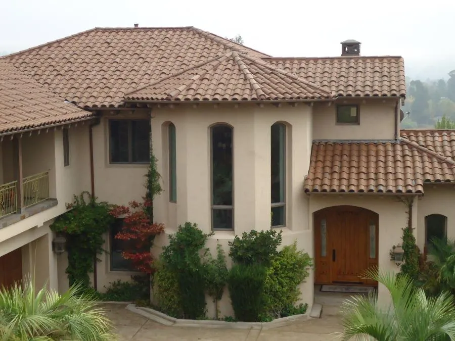  Mediterranean-style house with terracotta roof, tall arched windows, and surrounding greenery.