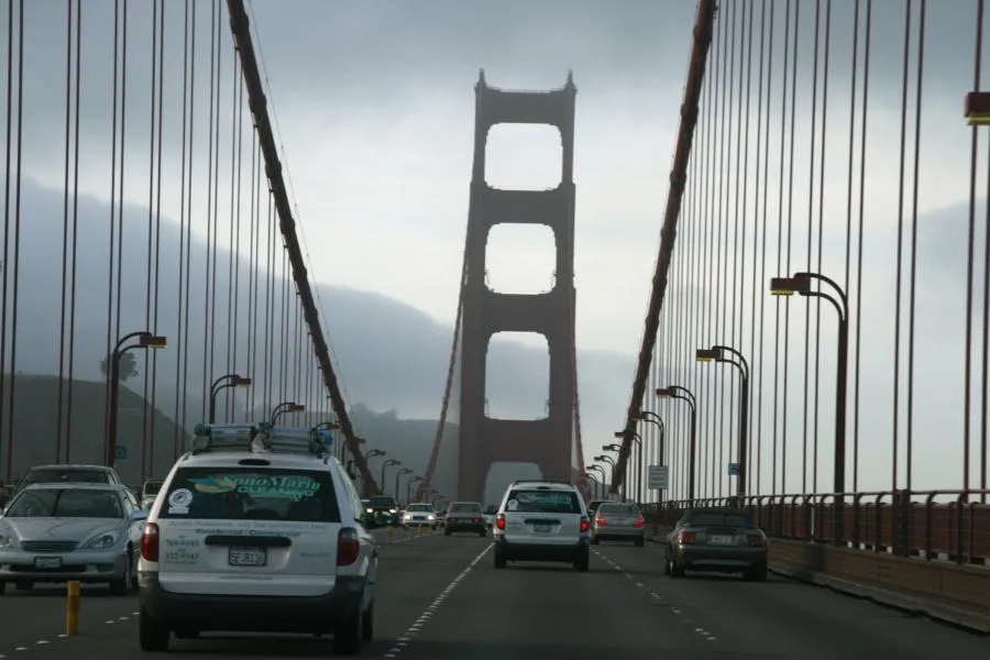 Cars drive across the Golden Gate Bridge in overcast weather, with a SonoMarin Cleaning Services, Inc. vehicle visible in the foreground.