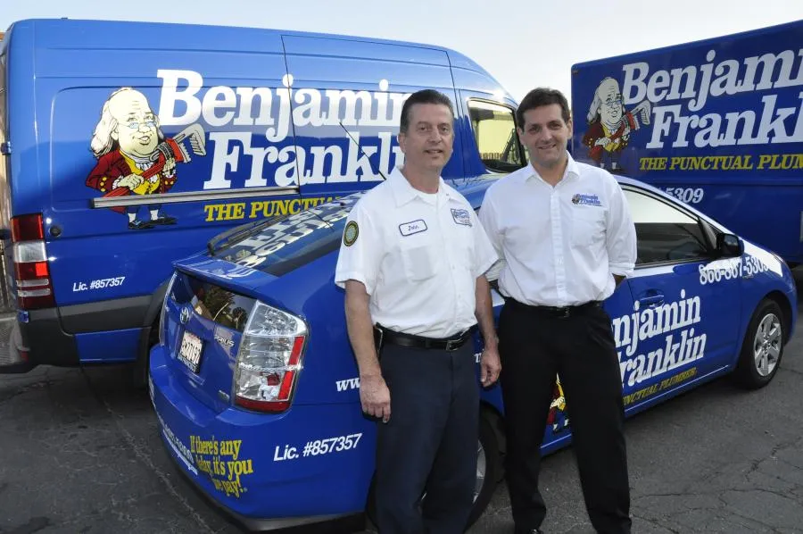 Picture of Two members of Benjamin Franklin Plumbing stand confidently beside branded service vehicles, illustrating their commitment to punctuality and professionalism. The company is recognized for its expertise and quality. Copyright ©2025 Diamond Certified Resource - Benjamin Franklin Plumbing