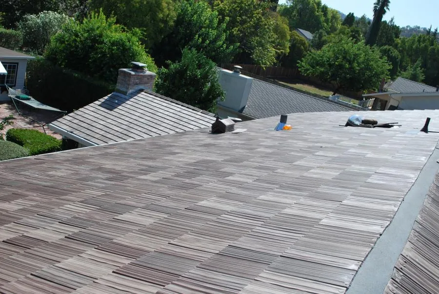  A detailed view of a rooftop with neatly installed shingles, surrounded by trees and neighboring homes.
