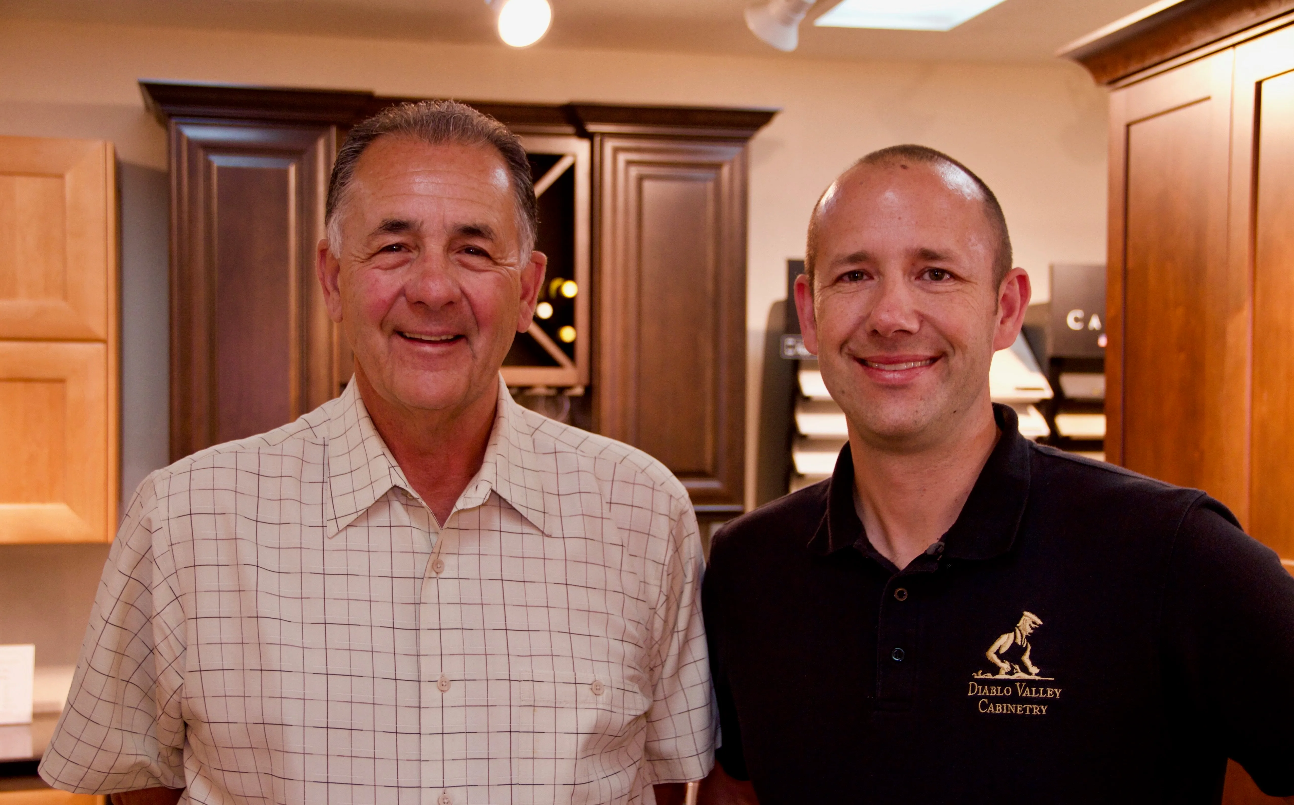Picture of In a warmly lit showroom, two team members of Diablo Valley Cabinetry stand proudly before meticulously crafted cabinets, reflecting the companyâ€™s focus on quality outcomes. Copyright ©2025 Diamond Certified Resource

 - Diablo Valley Cabinetry