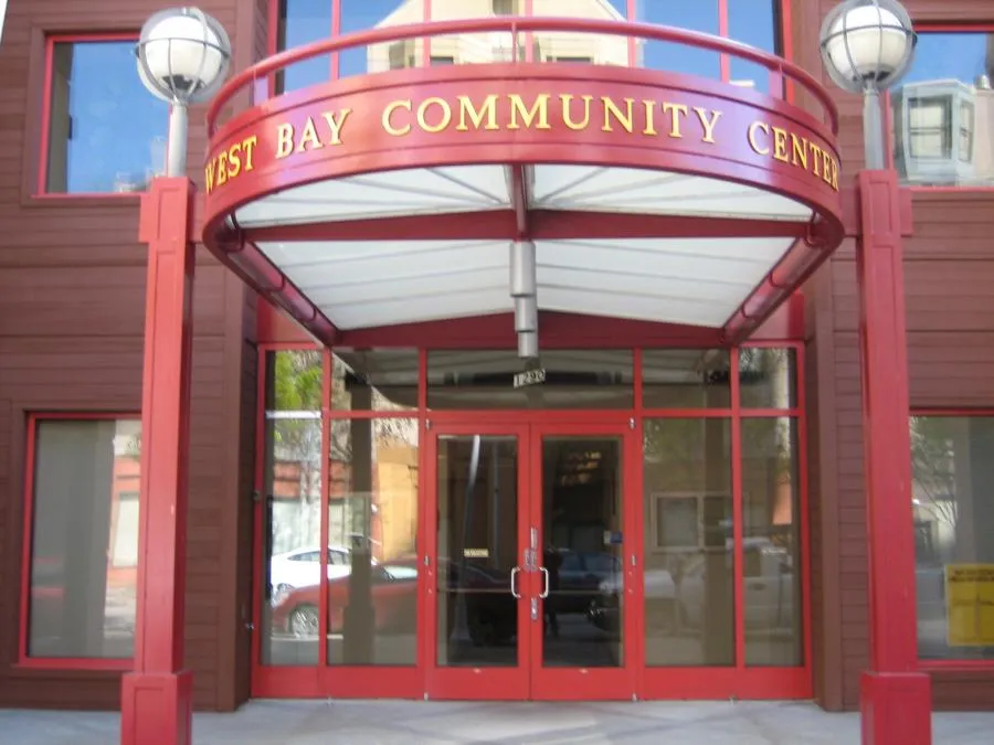  Front view of West Bay Community Center with a red entrance structure and glass doors.
