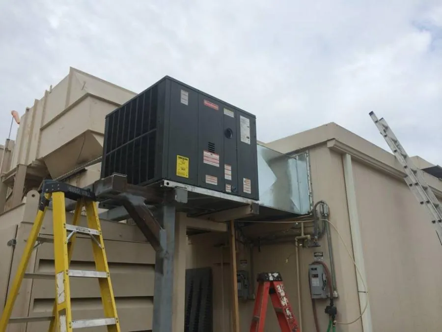 Rooftop HVAC unit installation with ladders and electrical boxes visible; overcast sky in the background. Rooftop HVAC unit installation with ladders and electrical boxes visible; overcast sky in the background.