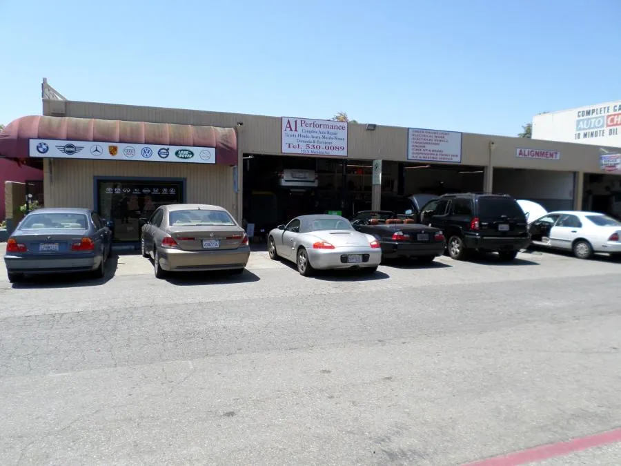  Exterior of A1 Performance Auto Repair with several cars parked in front, including a Porsche and BMW. Signs for various car brands and services are visible.