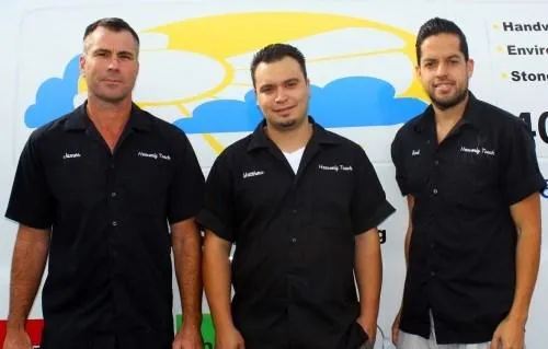  Three men wearing black shirts with "Heavenly Touch" logos stand in front of a van featuring a colorful cloud design.