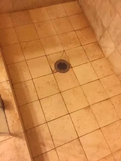 Close-up of a clean tiled shower floor with a central drain.