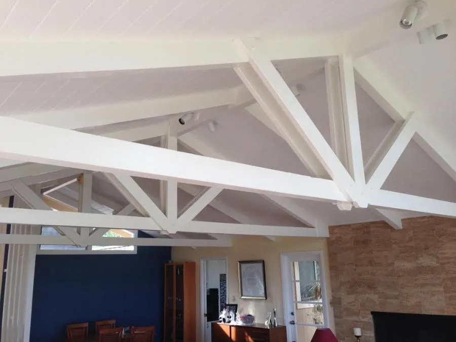 Interior view of a room with vaulted ceilings featuring exposed white-painted beams, a blue accent wall, and a fireplace.
