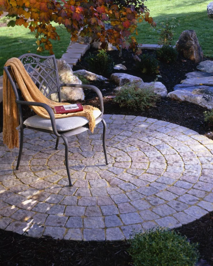 Picture of Amidst a serene garden, a chair with a warm blanket beckons on a meticulously crafted stone patio by Black Diamond Paver Stones & Landscape, Inc., a company recognized for expertise and quality. Copyright ©2025 Diamond Certified Resource. - Black Diamond Paver Stones & Landscape, Inc.